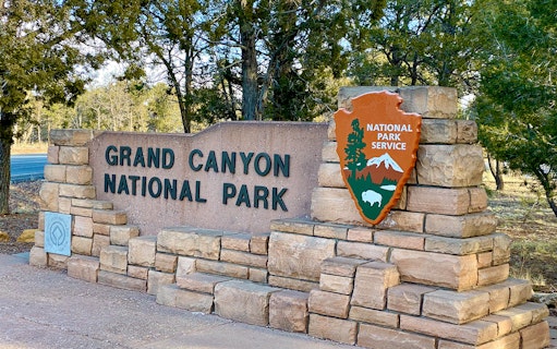 Grand Canyon National Park entrance sign with National Park Service emblem.