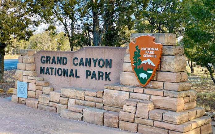 Grand Canyon National Park entrance sign with National Park Service emblem.