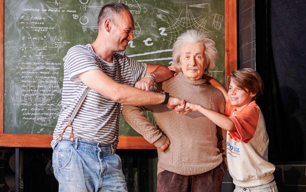 Albert Einstein wax figure with visitors at Madame Tussauds, Berlin.