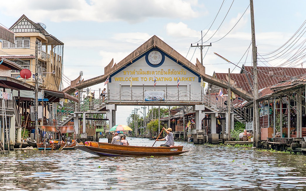 Damnoen Saduak Floating Market entrance with boats on the canal, Thailand.