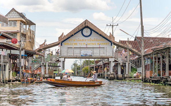 Damnoen Saduak Floating Market entrance with boats on the canal, Thailand.