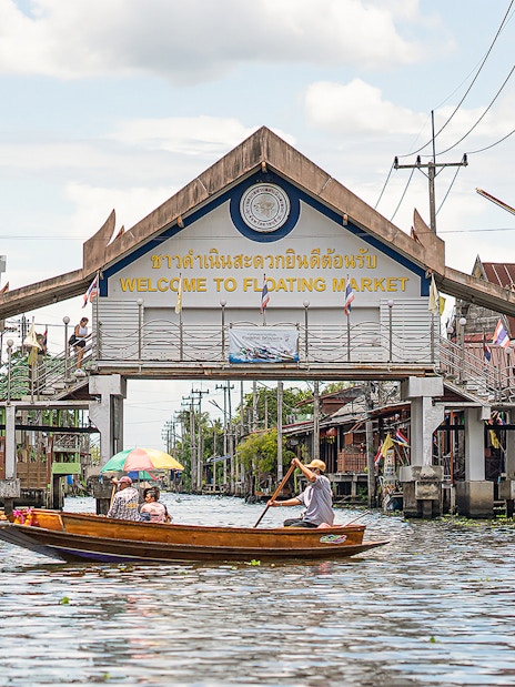 Damnoen Saduak Floating Market entrance with boats on the canal, Thailand.