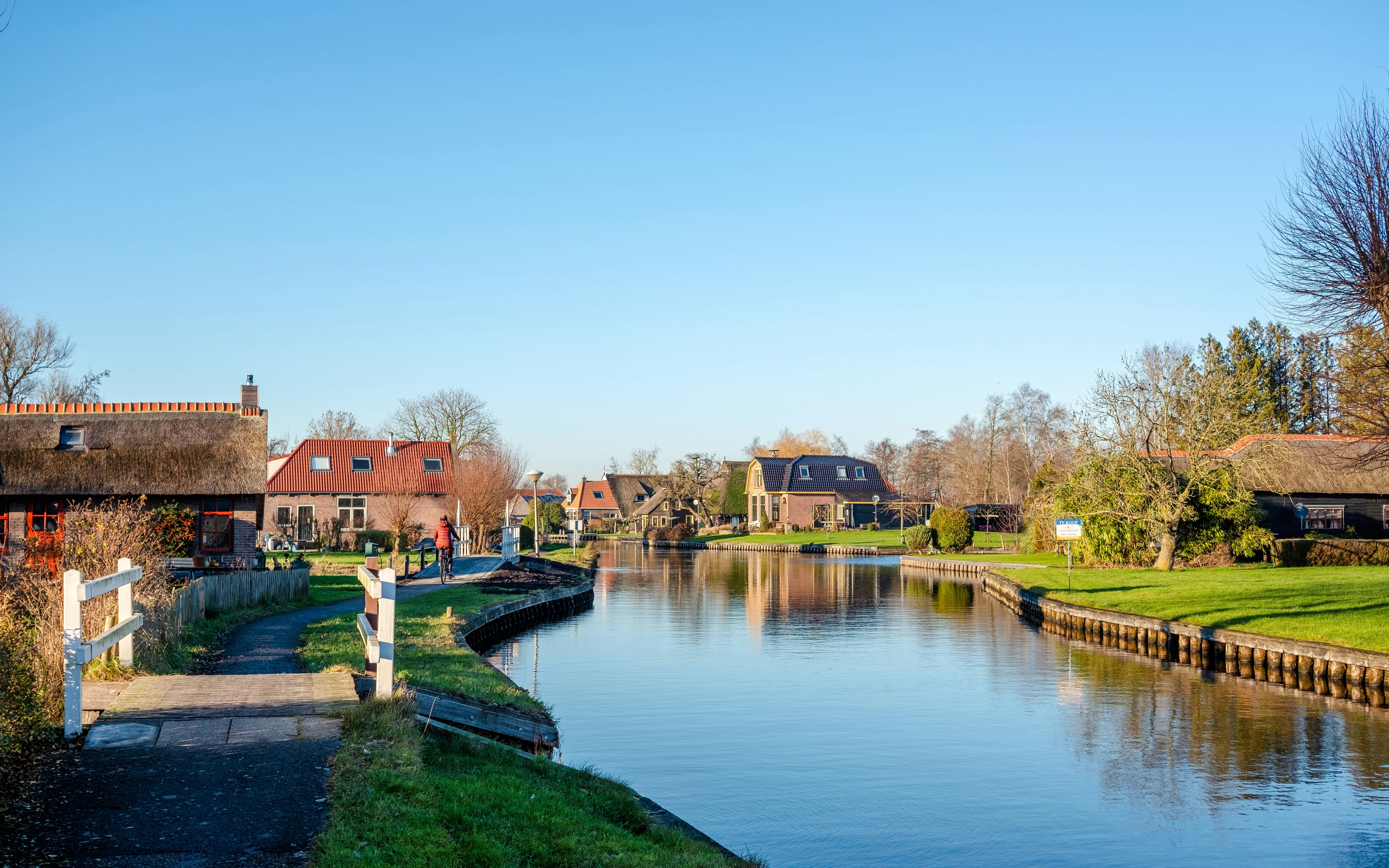 Canal view in Giethoorn, Amsterdam with traditional houses and a pedestrian bridge in winter.