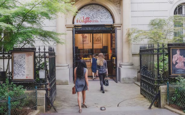 Visitors entering the Cernuschi Museum in Paris through an ornate gate.