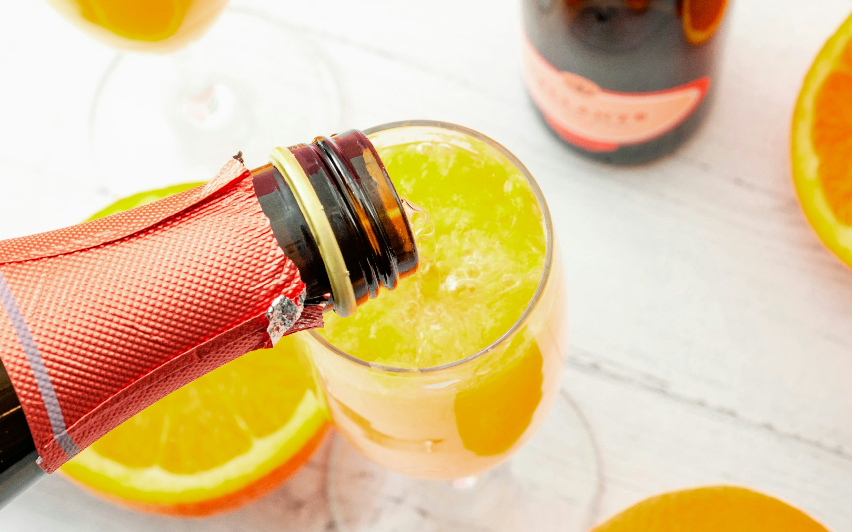 Pouring champagne into a glass of orange juice for mimosas.