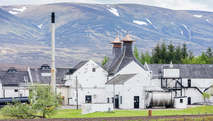 Whisky distillery with pagoda roofs in Scottish Highlands landscape.