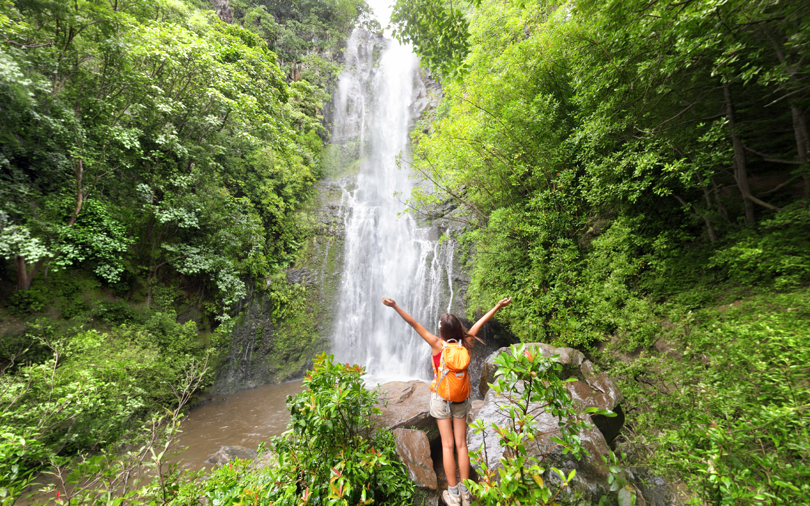 Person enjoying a waterfall on the Road to Hana Adventure Tour, Maui, Hawaii.