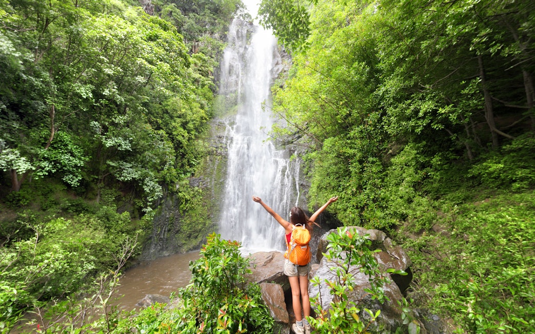 Person enjoying a waterfall on the Road to Hana Adventure Tour, Maui, Hawaii.