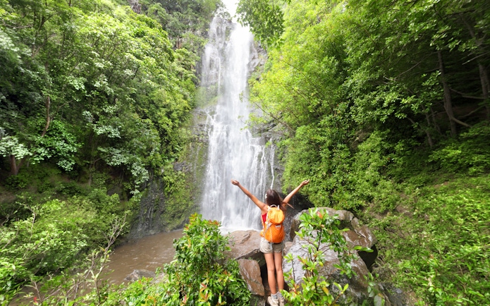 Person enjoying a waterfall on the Road to Hana Adventure Tour, Maui, Hawaii.
