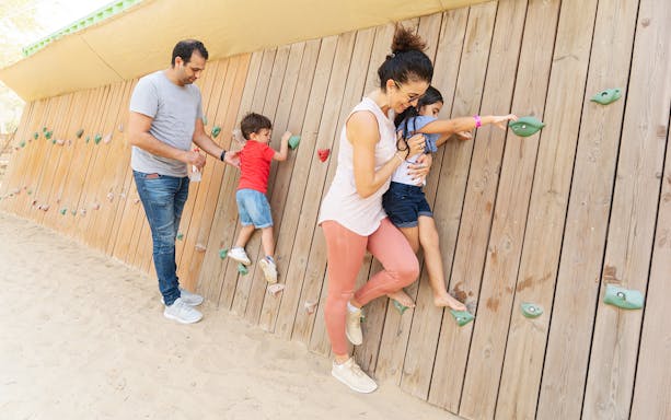 Family enjoying climbing wall in kids play area at Aventura Parks.