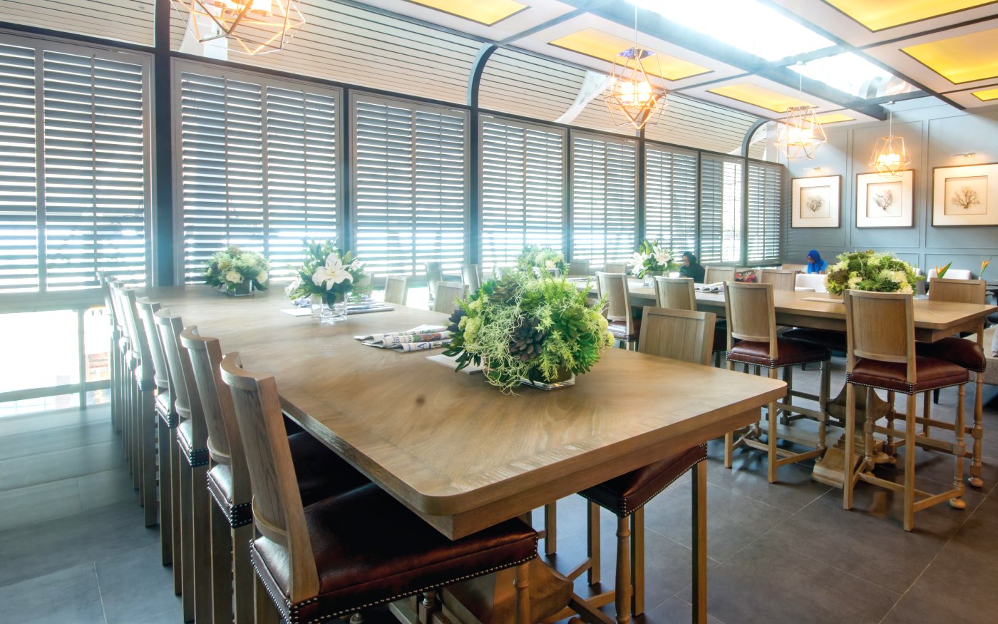 Coral Executive Lounge seating area with wooden tables and floral arrangements at Phuket International Airport.