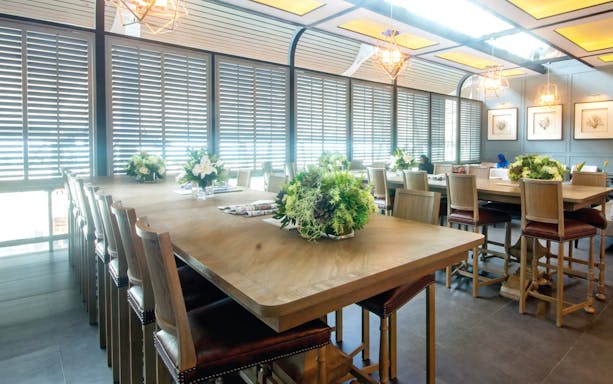 Coral Executive Lounge seating area with wooden tables and floral arrangements at Phuket International Airport.