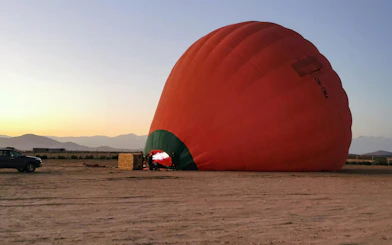 Hot air balloon inflating at sunrise in Marrakech desert.