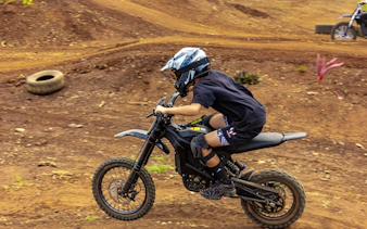 Young rider on an electric dirt bike navigating a dirt track in Oahu.