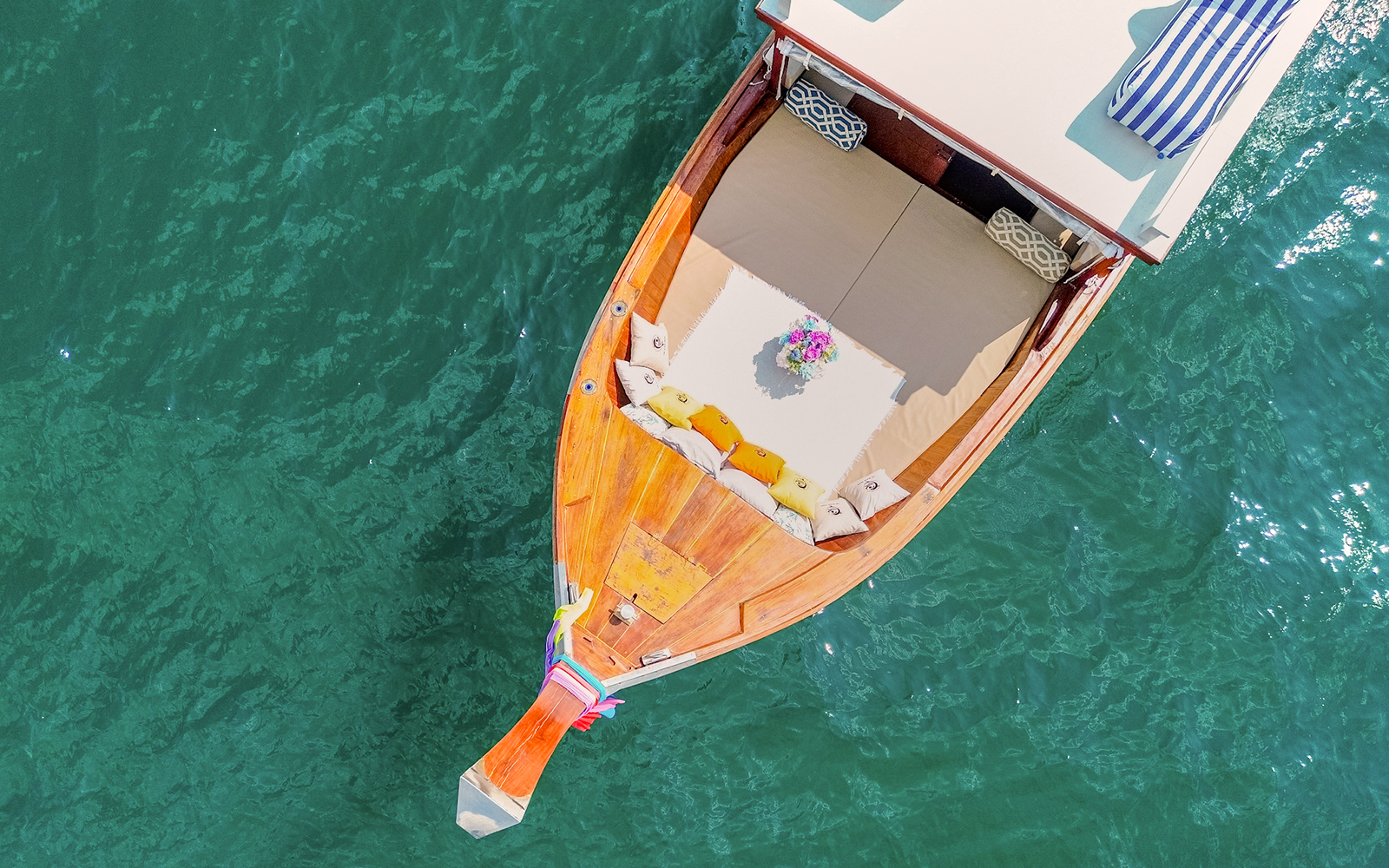 Long tail boat with cushions and flowers on turquoise water in Krabi, Thailand.