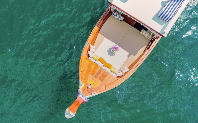 Long tail boat with cushions and flowers on turquoise water in Krabi, Thailand.