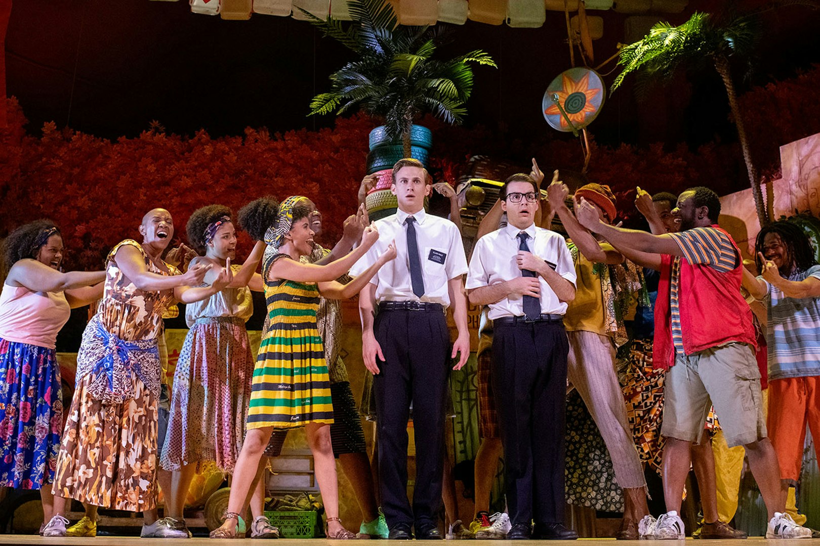 Performers on stage during "The Book of Mormon" musical scene with vibrant costumes.