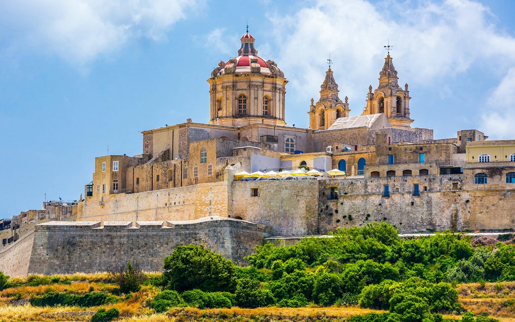 Mdina cityscape with historic architecture under a blue sky, Malta.