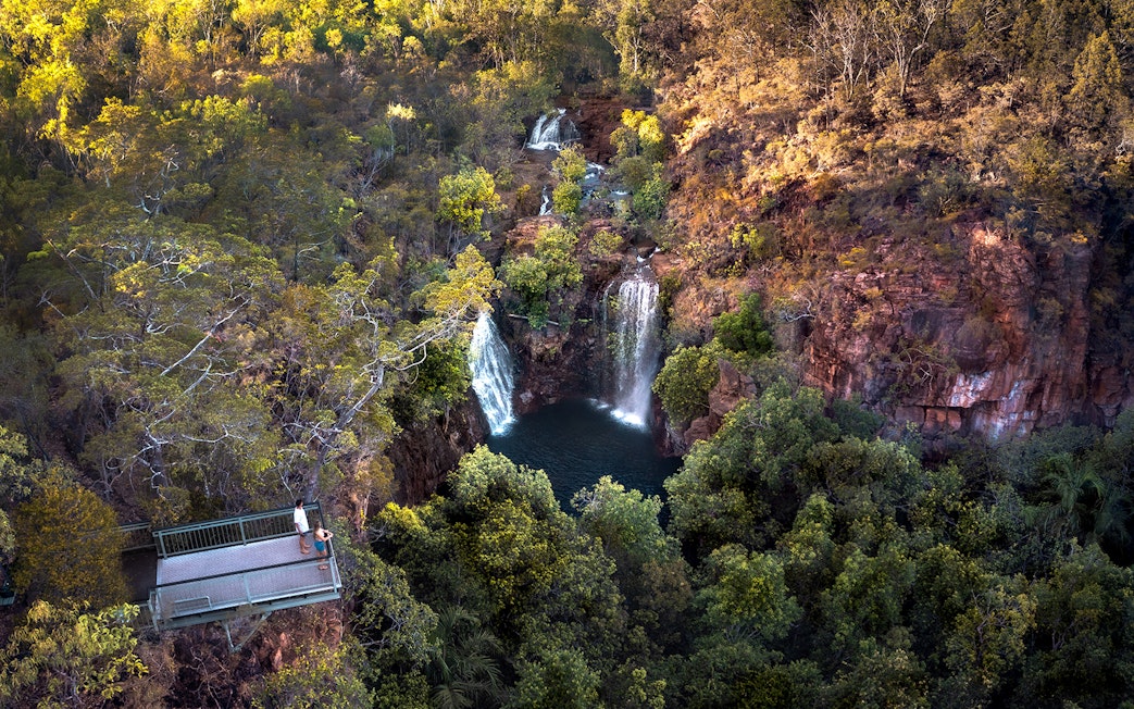 Litchfield National Park waterfall view from lookout platform, surrounded by lush greenery.