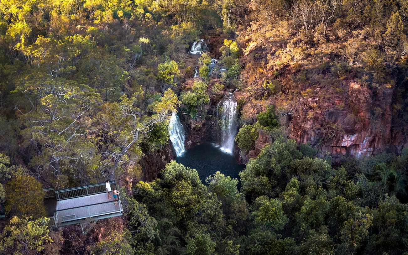 Litchfield National Park waterfall view from lookout platform, surrounded by lush greenery.