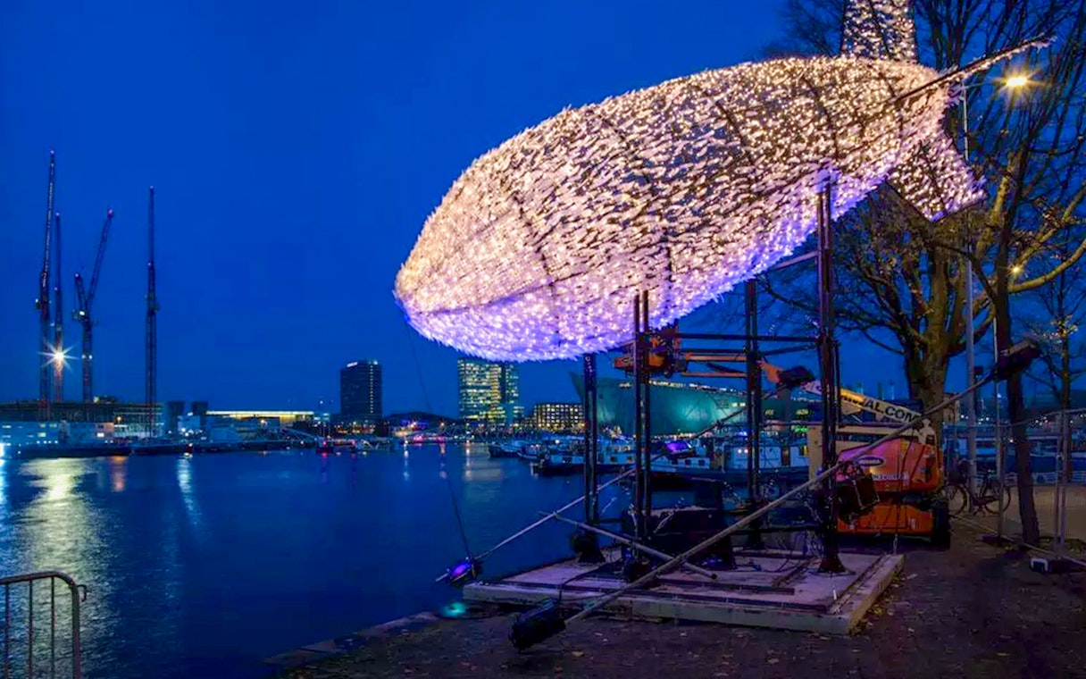 Amsterdam Light Festival installation of illuminated fish sculpture by the waterfront.
