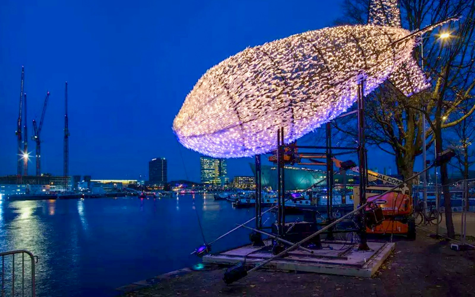 Amsterdam canal boat passing illuminated art installations during Light Festival.