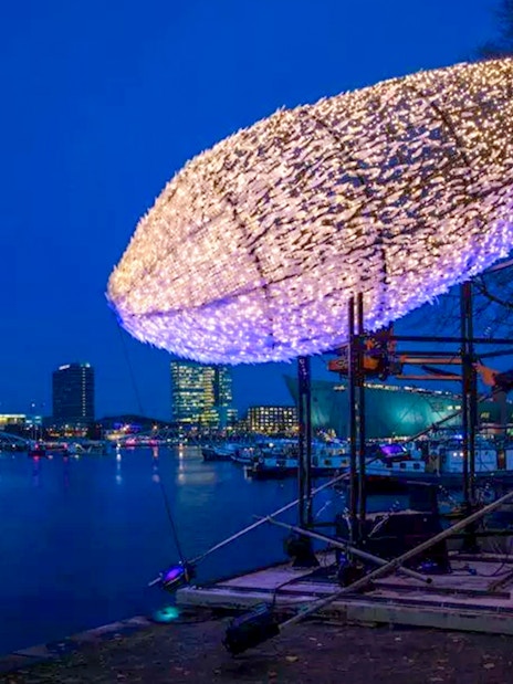 Amsterdam Light Festival installation of illuminated fish sculpture by the waterfront.
