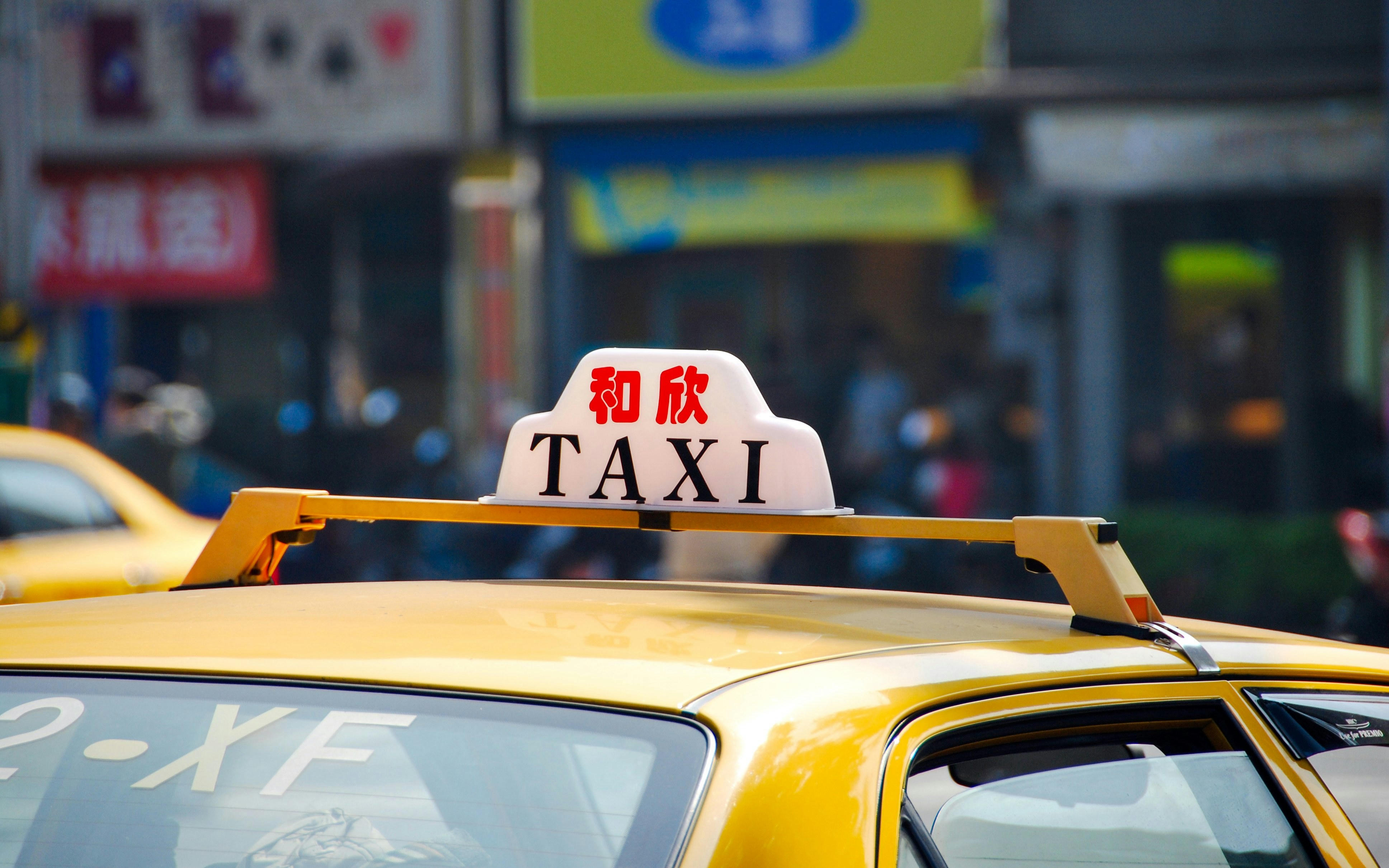 Yellow taxi with rooftop sign in Taiwan street.