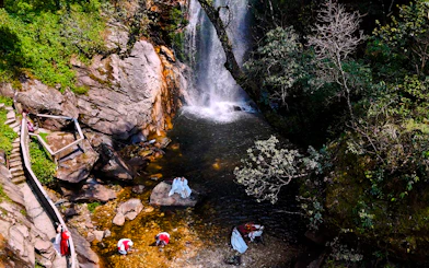 Waterfall and visitors at O Quy Ho Fairy Heaven Gate, Sa Pa, with rocky path and greenery.