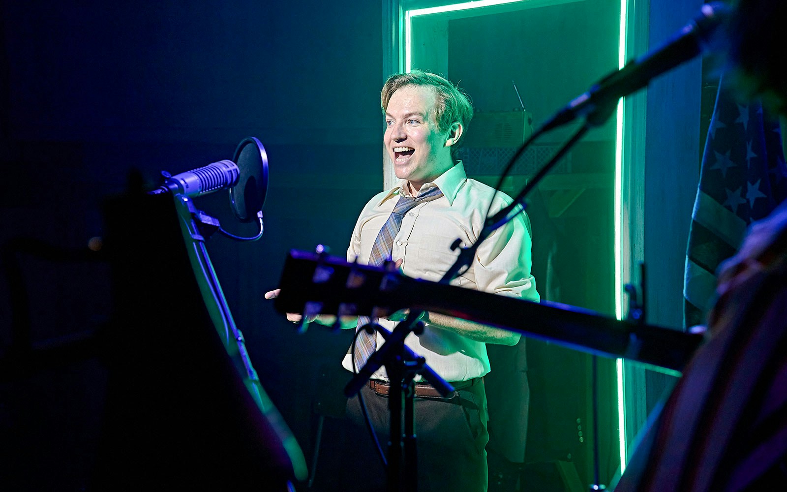 Performer on stage during Kenrex show with microphone and guitar in foreground.