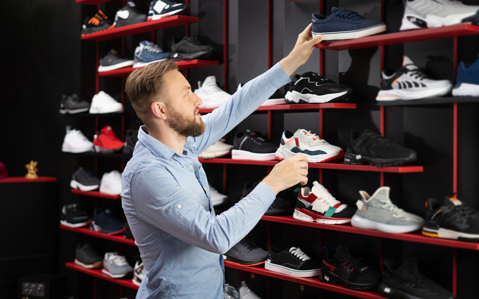 Man selecting sneakers from a shoe store display.