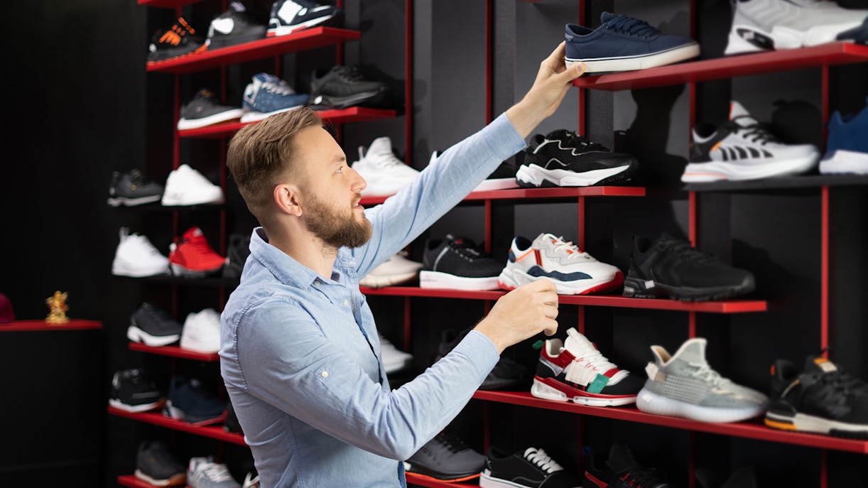 Man selecting sneakers from a shoe store display.