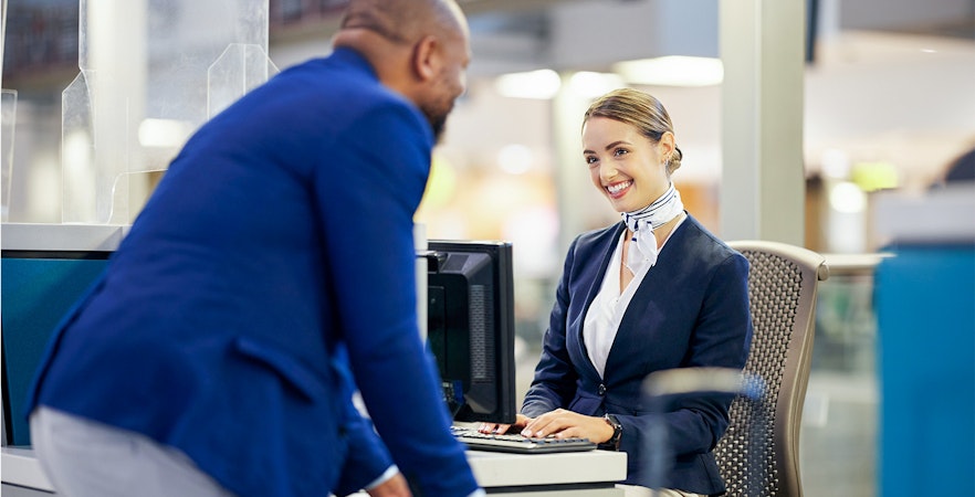 Airport staff assisting traveler at Rome airport transfer desk.