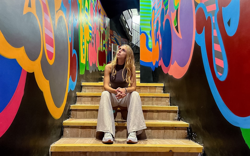 Visitor sitting on stairs, observing colorful graffiti at Moco Museum, Barcelona.