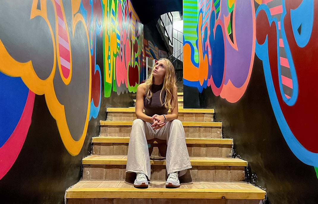 Visitor sitting on stairs, observing colorful graffiti at Moco Museum, Barcelona.
