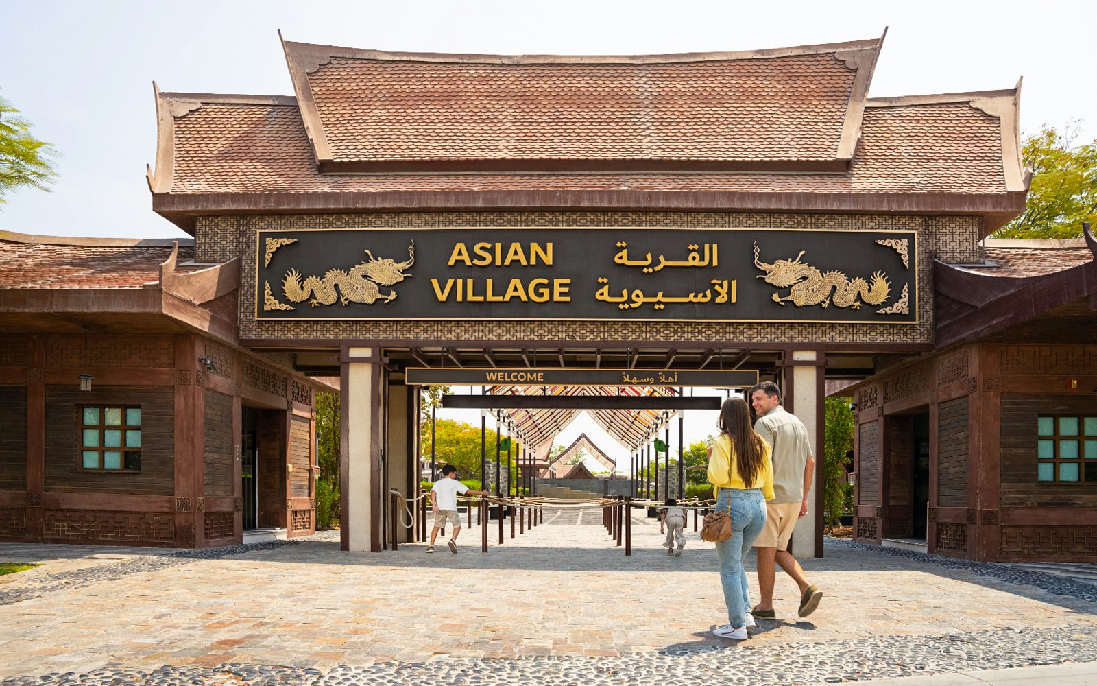 Entrance to Asian Village at Dubai Safari Park with visitors walking in.
