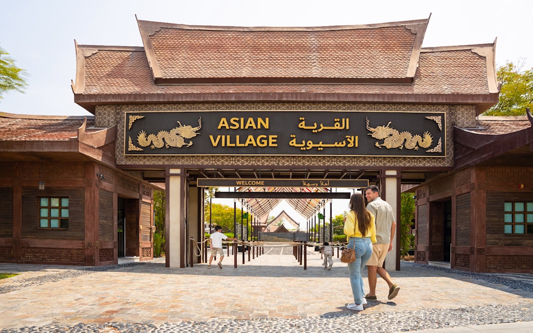 Entrance to Asian Village at Dubai Safari Park with visitors walking in.