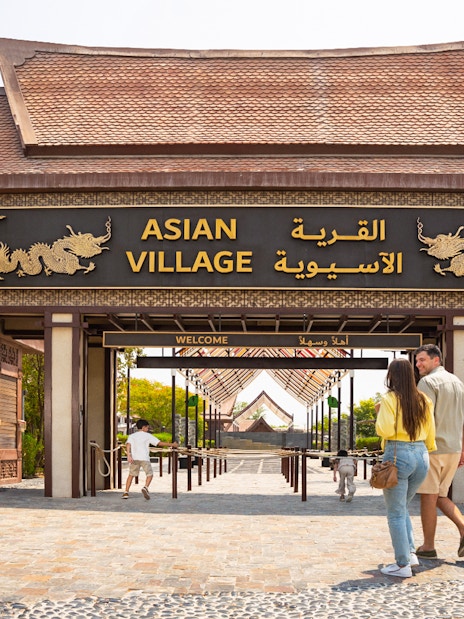 Entrance to Asian Village at Dubai Safari Park with visitors walking in.