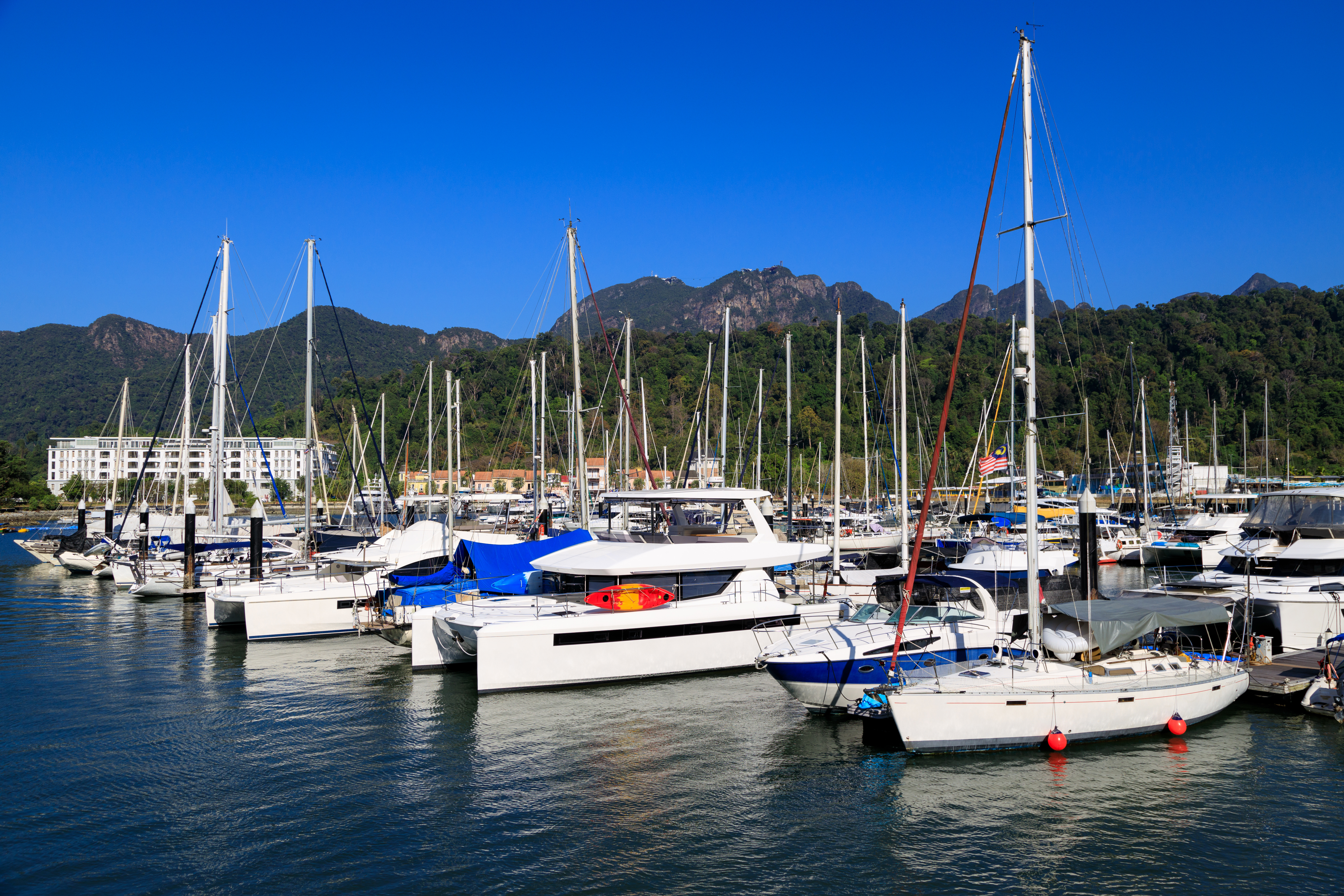 Boats docked at Telaga Harbor in Langkawi with lush green hills in the background.