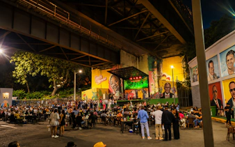 Outdoor live music event under bridge with audience and colorful murals in Santo Domingo, Punta Cana.