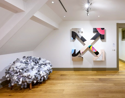 KAWS artwork and plush chair at Moco Museum, Amsterdam art tour.