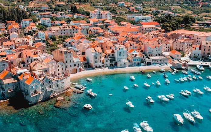 Aerial view of Hvar island's coastal town with boats in turquoise water.