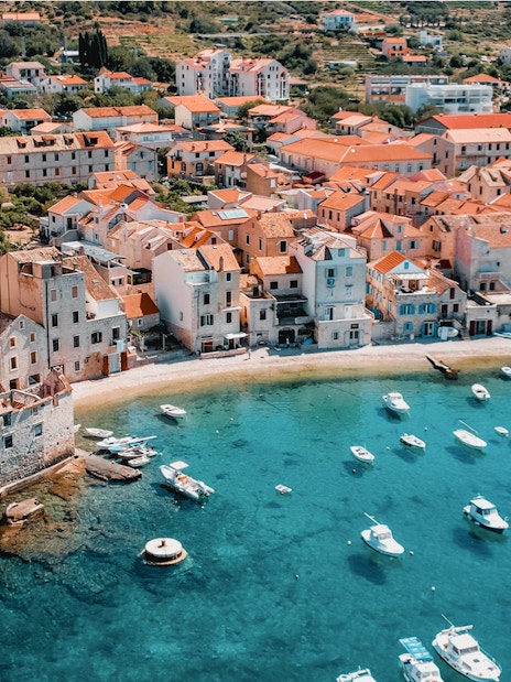 Aerial view of Hvar island's coastal town with boats in turquoise water.