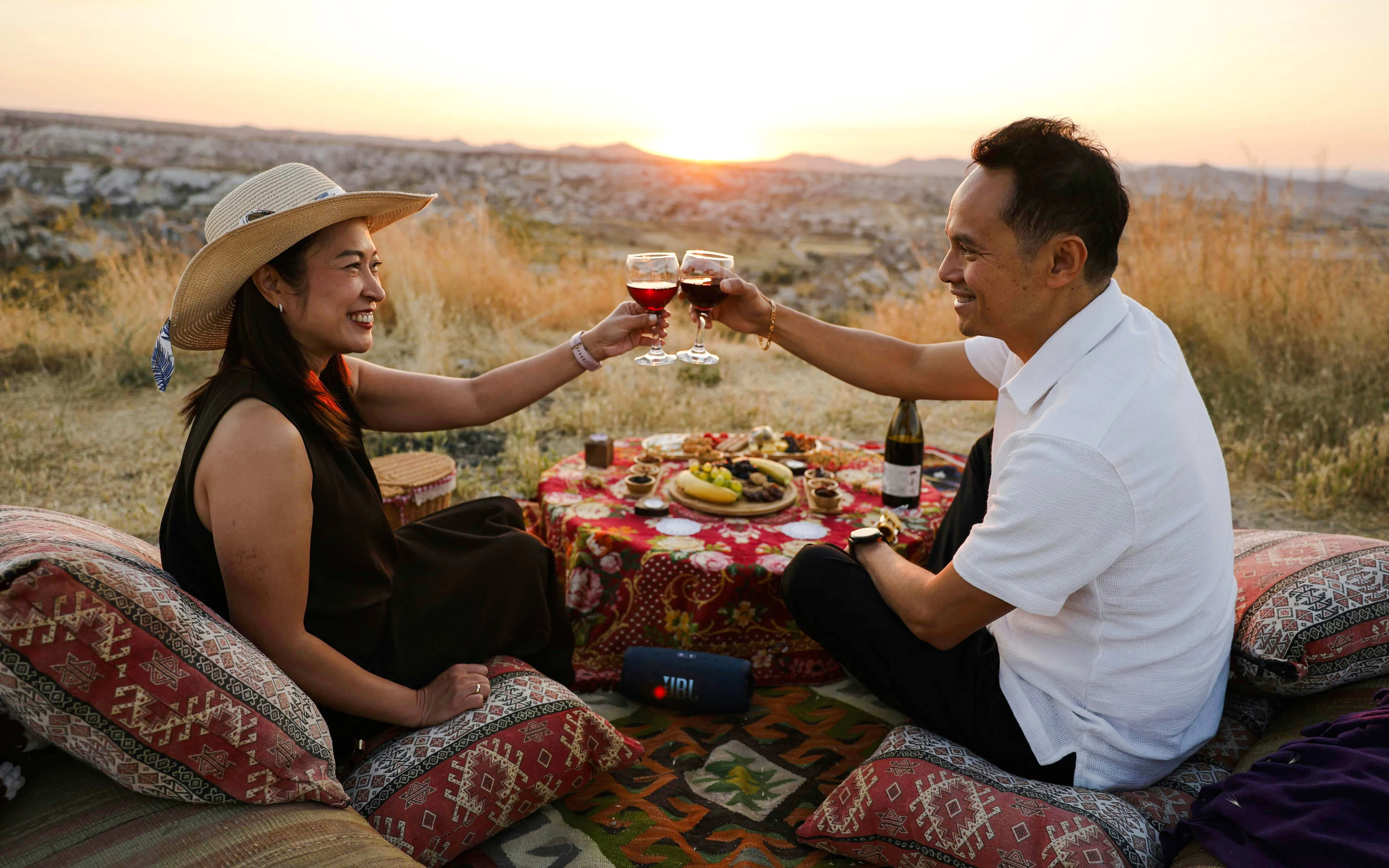 Couple enjoying a sunset picnic with wine in Cappadocia, Turkey.