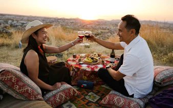 Couple enjoying a sunset picnic with wine in Cappadocia, Turkey.