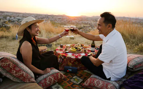 Couple enjoying a sunset picnic with wine in Cappadocia, Turkey.