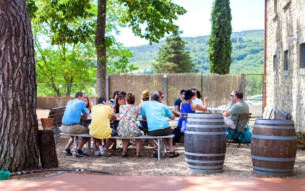 Group enjoying wine tasting outdoors in Chianti countryside.
