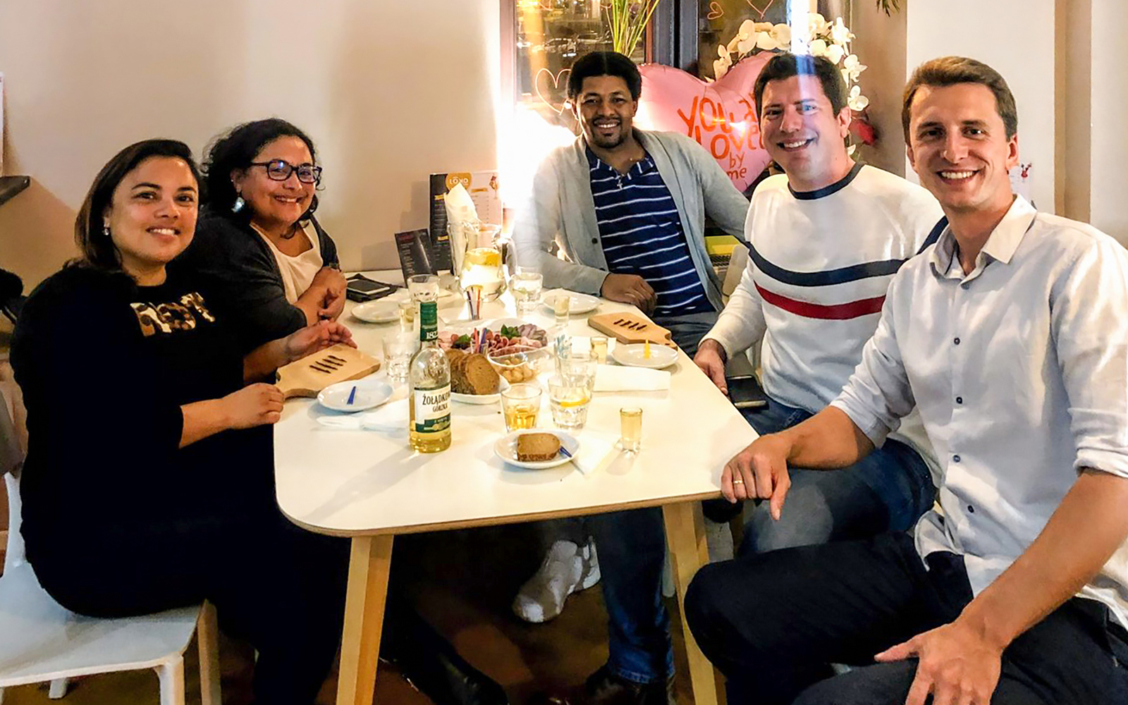 Group enjoying vodka tasting experience in Wroclaw with snacks and drinks on the table.