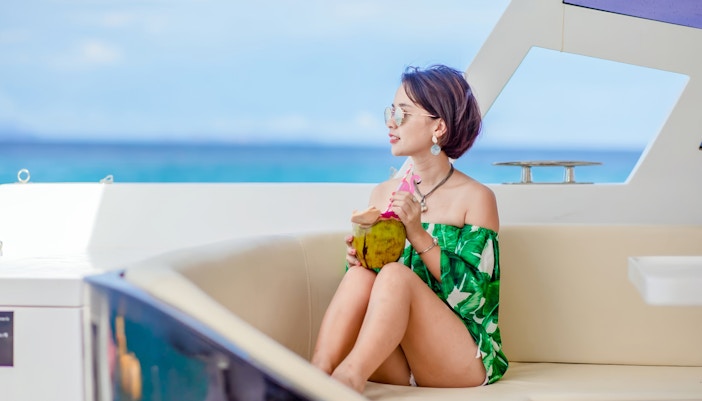 Lady enjoying a fresh coconut on a power catamaran