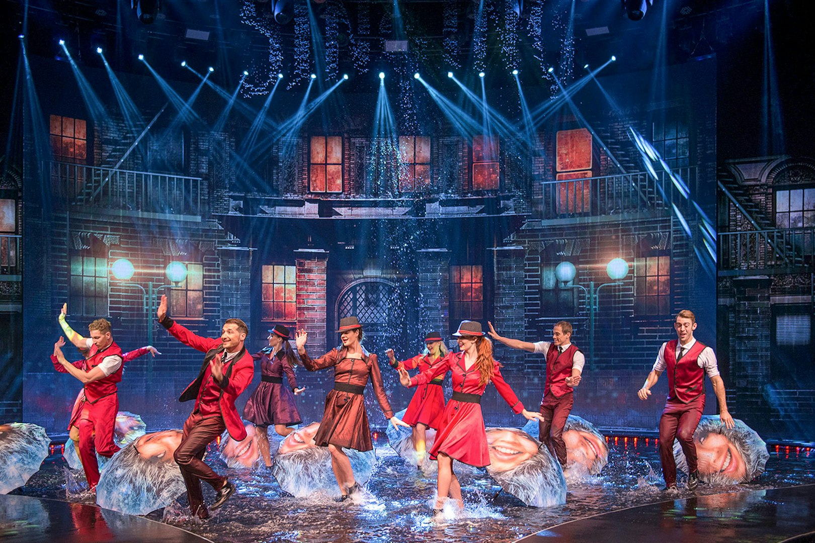 Performers dancing with umbrellas on a water-filled stage at WOW: The Vegas Spectacular.